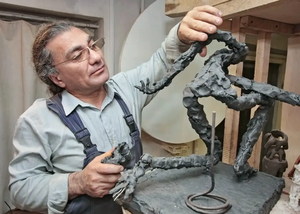Man sculpting human form in his studio.