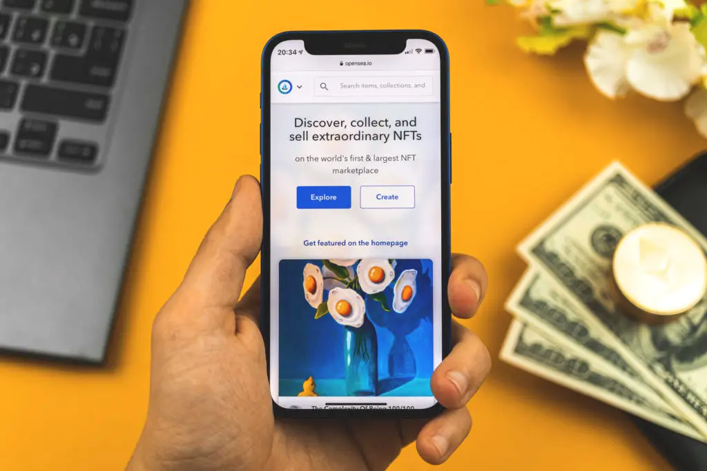 Phone showing NFT on OpenSea with cryptocurrency and US dollars in the background.
