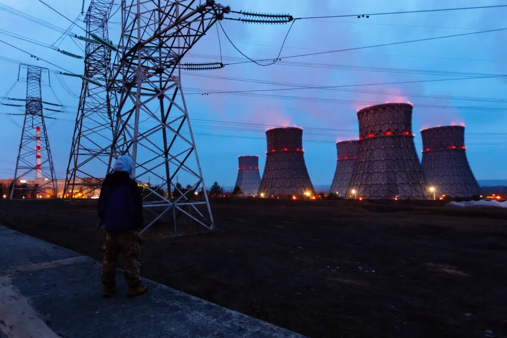 Man staring at nuclear power plant at night wondering if NFTs are stupid.