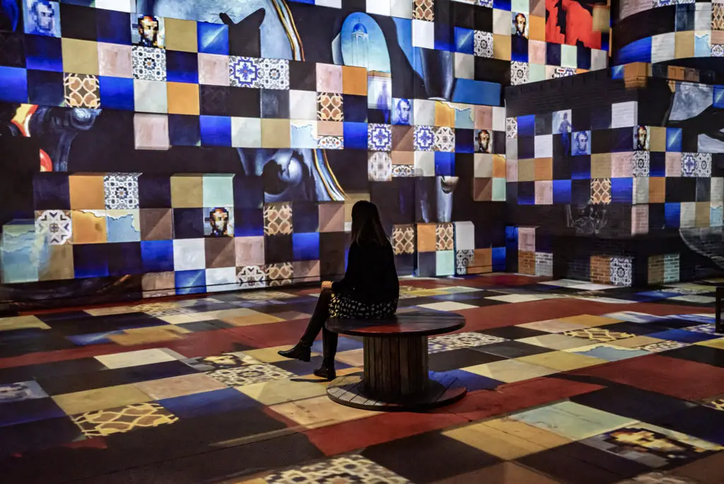 Woman sitting inside the Atelier des Lumières, an all digital paris art gallery