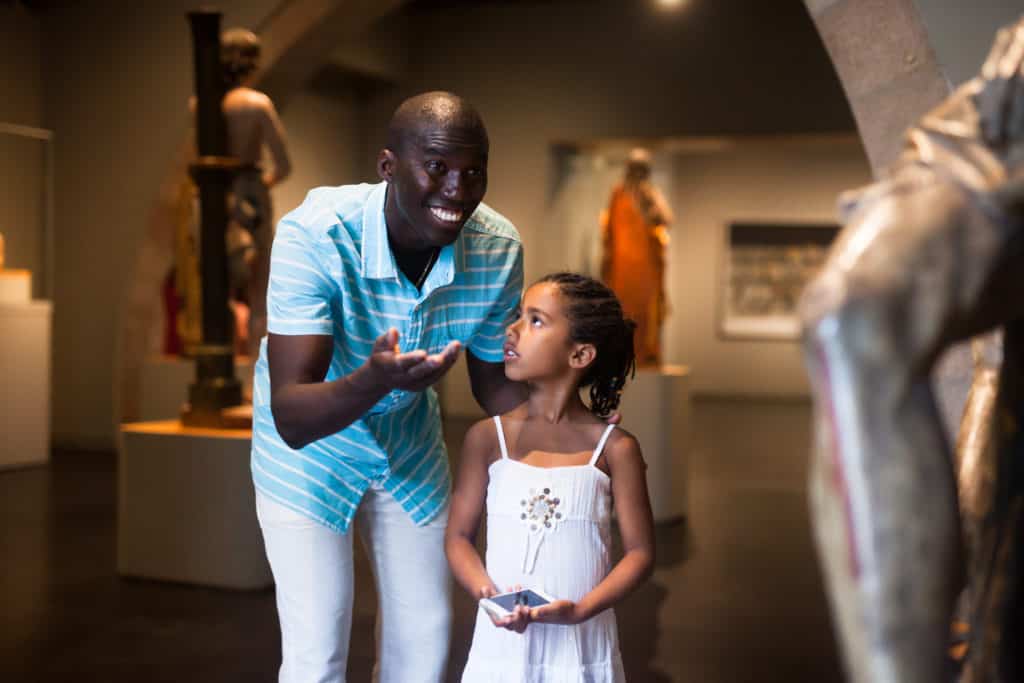Man showing his daughter a sculpture to teach how to appreciate art without becoming a snob.