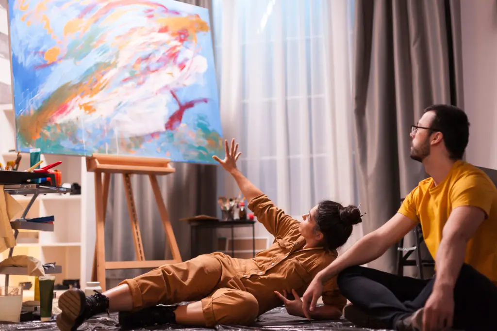 Female artist explaining to male with glasses why her painting is valuable.